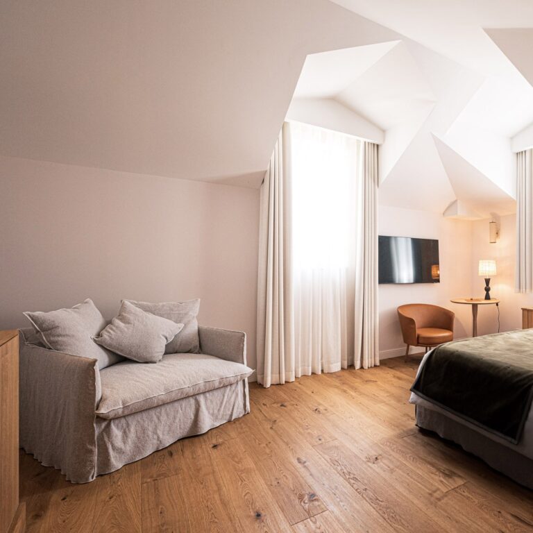 Sofa, TV et lit dans la Chambre la Tour de l'Hôtel Le Mosaïque, confort moderne.