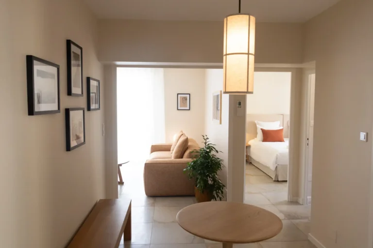 Intérieur de l'appartement lumineux avec sa table ronde en bois, ses cadres au mur, et l'ouverture sur le salon et la chambre.