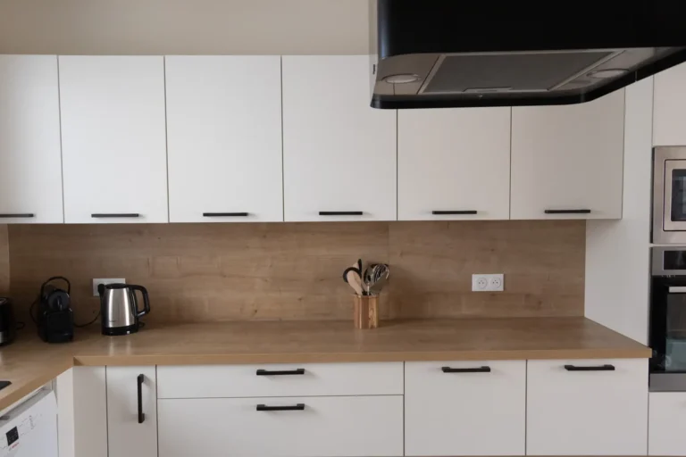 La cuisine de l'appartement, équipée de placards blancs et d'un plan de travail effet bois.