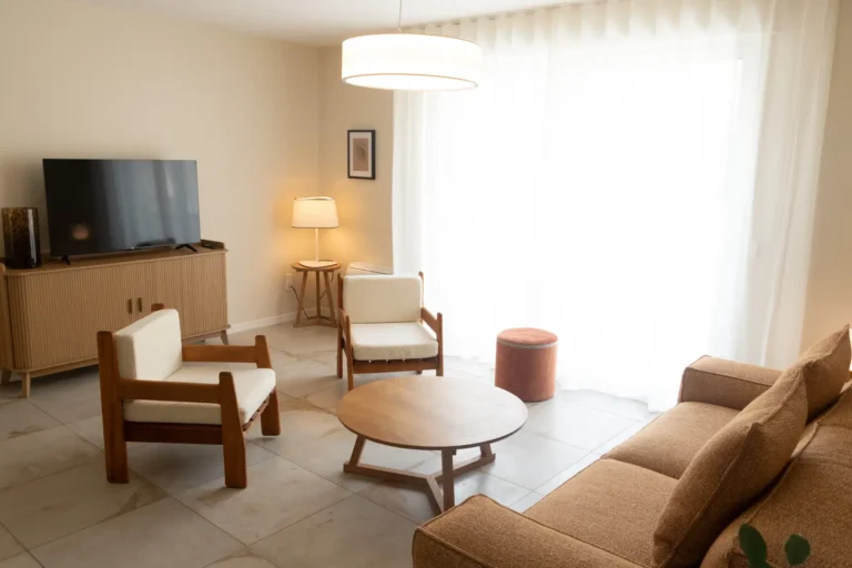 Le salon de l'appartement avec son canapé, ses fauteuils et sa table basse en bois.